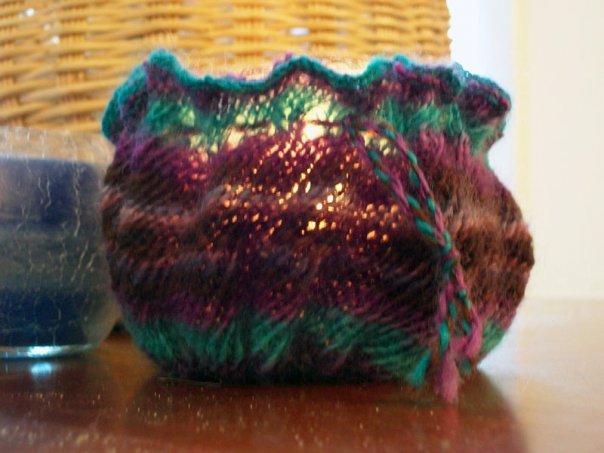 Knitted candle holder with lite candle. Knitting shows biasing from the twist.